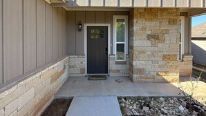 A modern house with a stone facade, a dark front door, and a small entryway with a welcome mat.