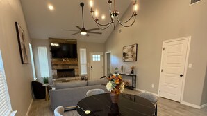 A dining area with a round table, four chairs, and a chandelier.