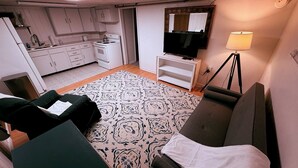 A compact living space with a kitchenette, a sofa, a TV, and a lamp. - Serene 2-bedroom apartment in Provo (Provo)