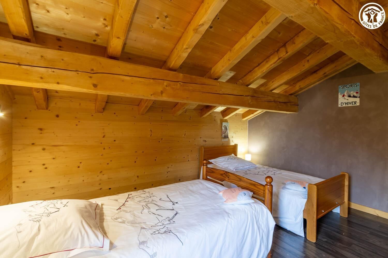 A wooden cabin room with two beds, a wooden ceiling, and a sign on the wall.