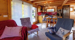 Interior acogedor de una cabaña con comedor, cocina y un amplio ventanal.