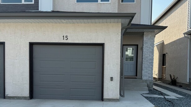 Une maison à deux étages avec un garage, une allée et une pelouse bien entretenue.