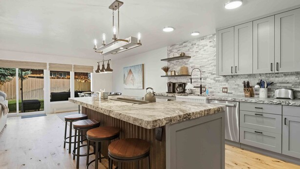 A modern kitchen with a large island, bar stools, and a view to the outside. - The Timberline House | Modern Mountain Comfort | Walk to Town & Near Lifts (Ketchum)