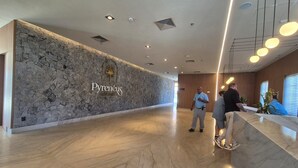 Una moderna hall d'hotel con parete in pietra, reception e pavimento in marmo.
