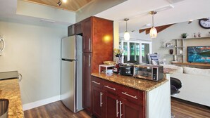 Une cuisine moderne dotée de plans de travail en granit, d’appareils électroménagers en acier inoxydable et d’armoires en bois.