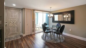 Un coin repas avec une table ronde et des chaises, un lustre et un grand miroir au mur.