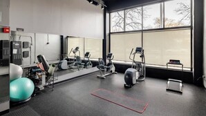 Een sportschool met trainingsapparatuur, een groot raam en een spiegel.