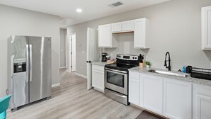 Une cuisine moderne avec des armoires blanches, des appareils en acier inoxydable et un comptoir en granit.