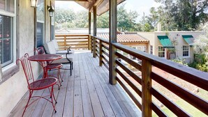 Een houten terras met een reling, een tafel en twee stoelen.