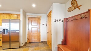 Un pasillo con un banco de madera, una puerta y un perchero en la pared.