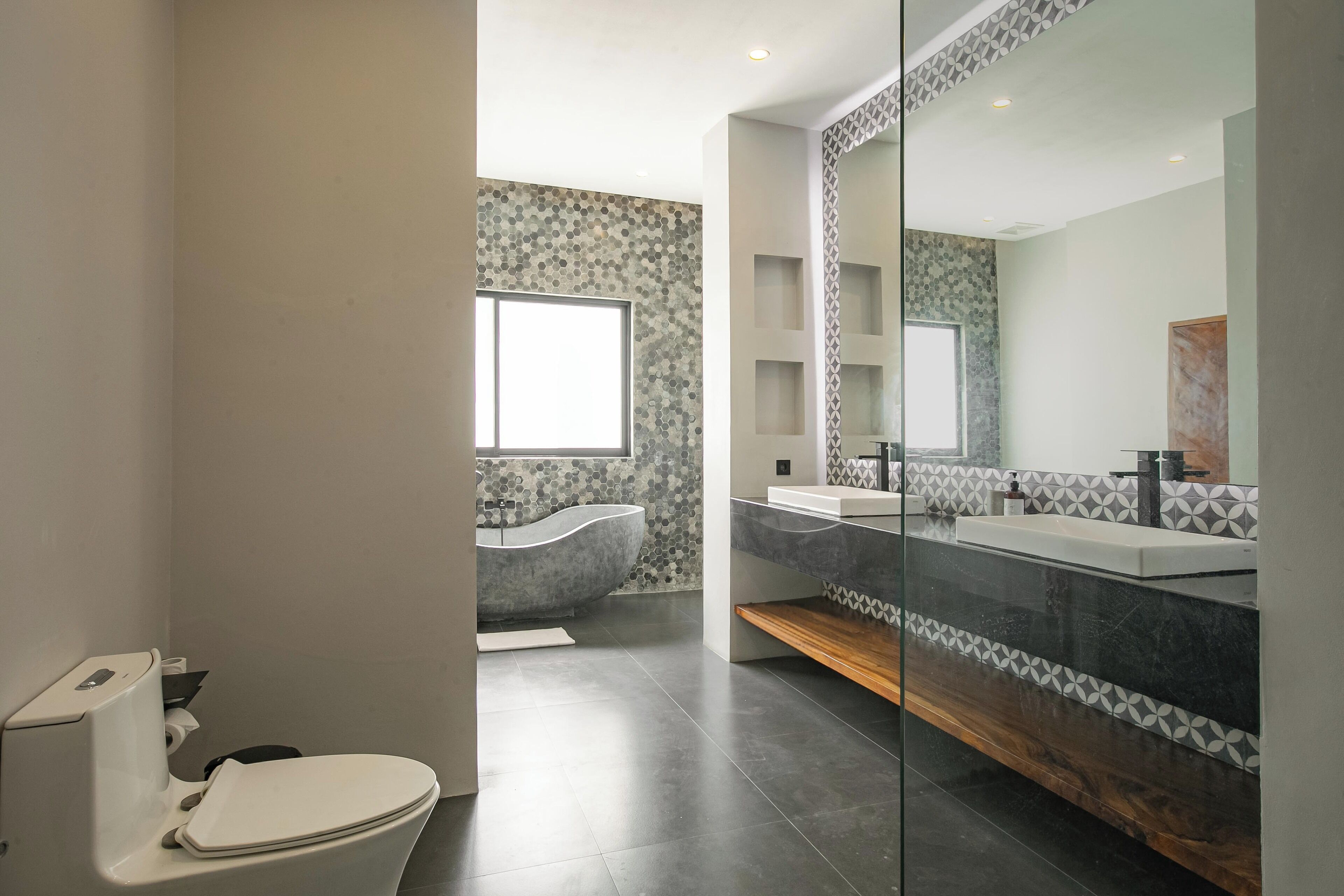 A modern bathroom with a toilet, a bathtub, and a vanity with a mirror.