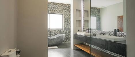 A modern bathroom with a toilet, a bathtub, and a vanity with a mirror.