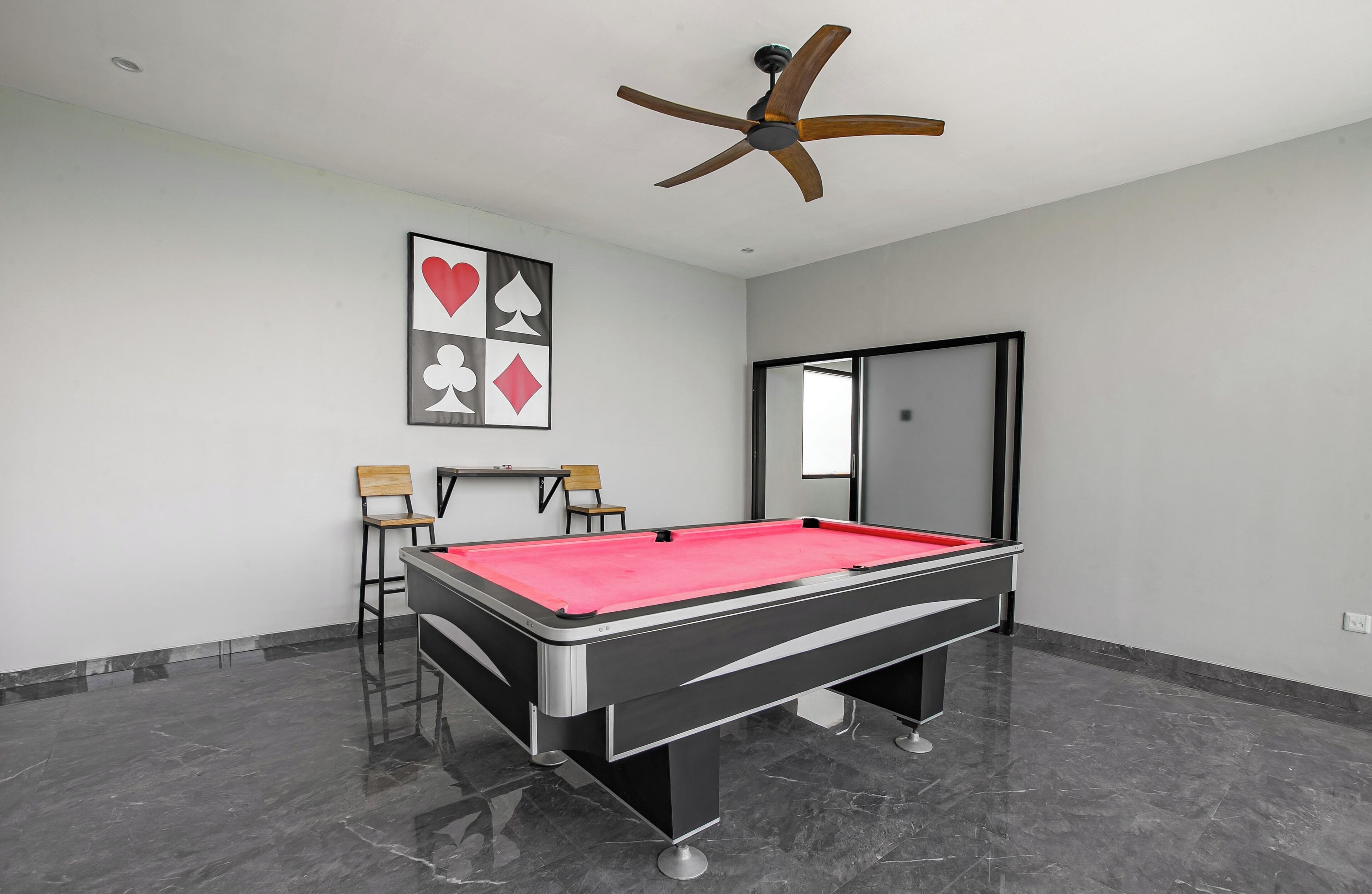 A room with a pool table, ceiling fan, and wall art.