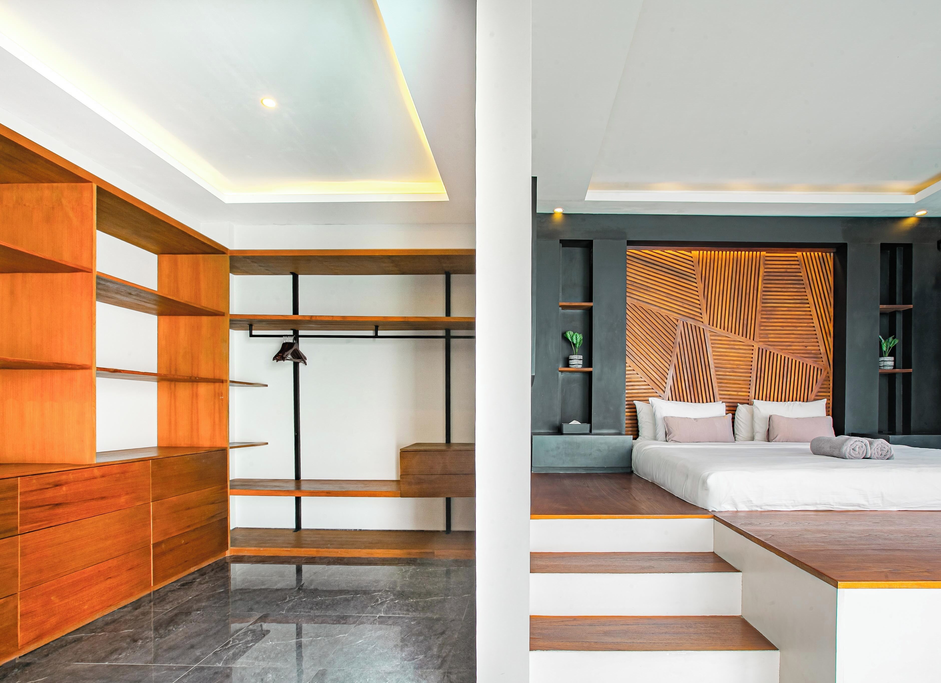 Une chambre moderne avec un lit, des étagères intégrées et un mur orné d’un motif géométrique.