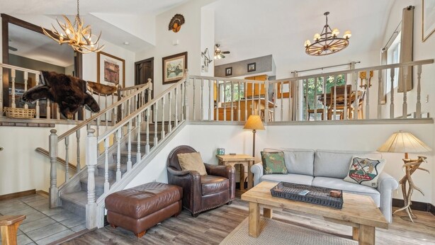 A spacious living room with a staircase, leather furniture, and a chandelier. - New! Large Patio, Dogs Allowed, Great Location! (Whitefish)