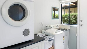 A compact laundry room with a washing machine, dryer, and a small sink. - Lakeview Retreat Bonnie Doon - Sleeps 11 (Bonnie Doon)