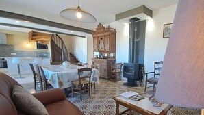 Ein Wohnzimmer mit einer Couch, einem Esstisch, Stühlen, einem Fernseher und einem Kamin.