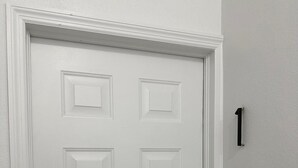 A white door with a keypad lock and a small number plaque on the wall. - Modern 2-bedroom apartment in Nassau, steps away from the beach. (Nassau)