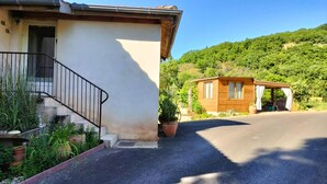 A two-story house with a staircase, a small wooden structure, and a driveway leading to a parked car. - Le Grenier d'Alfred - MOUZIEYS PANENS (MOUZIEYS PANENS)