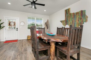 A dining area with a wooden table and chairs, a ceiling fan, and a window with blinds.