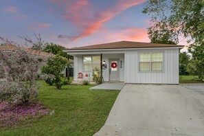 A single-story house with a front porch, a mailbox, and a front yard with a lawn and shrubs.