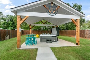 A covered outdoor patio with a grill, seating, and a logo on the roof.