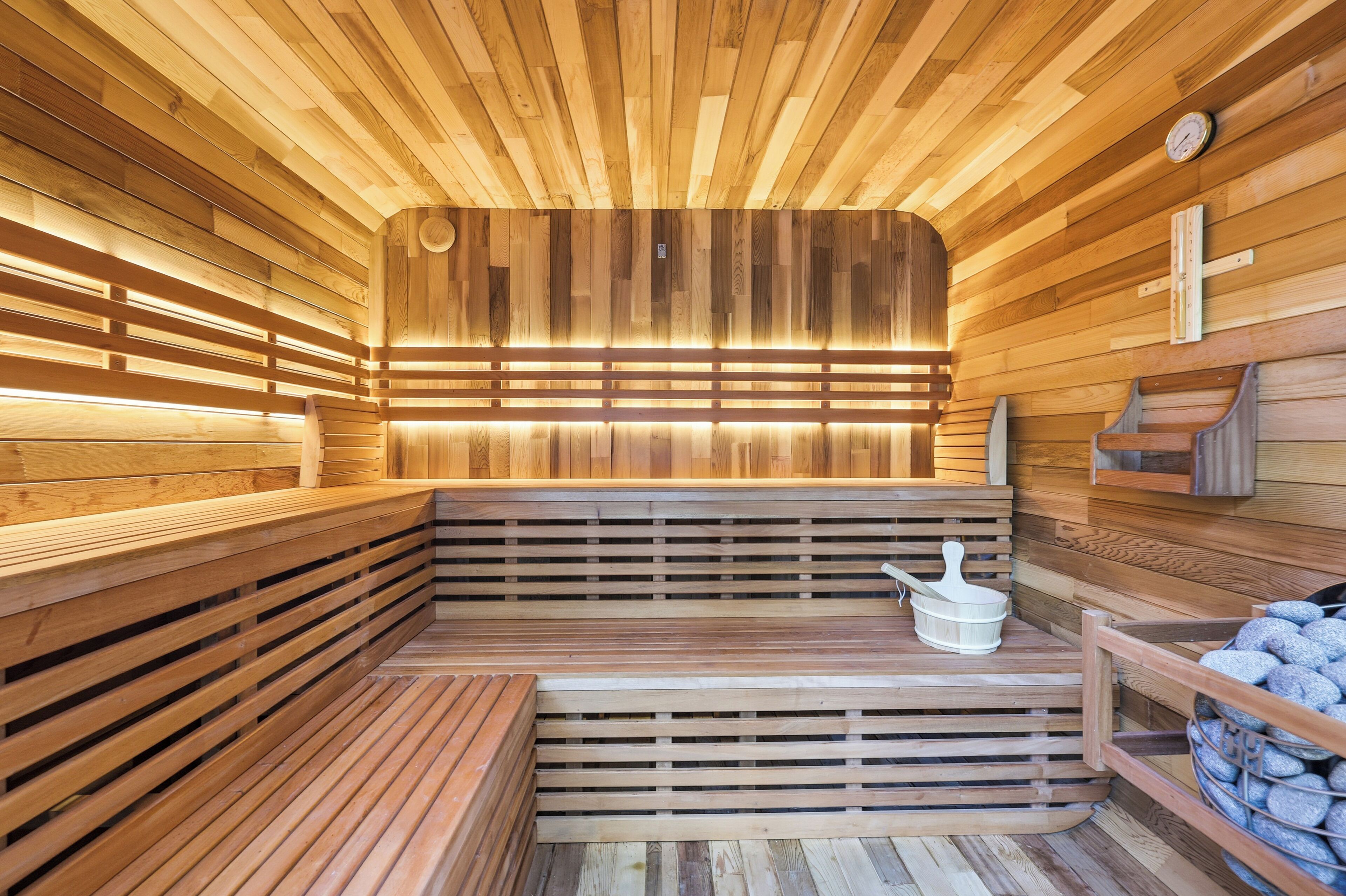Puisesta laudeseinästä tehty sauna, jossa on penkkejä ja erillinen penkki, jossa on ämpäri.