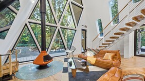 Un intérieur moderne avec une grande fenêtre, une cheminée, un escalier et un canapé.