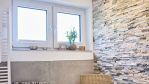 A bathroom with a stone wall, a wicker chair, a towel rack, and a window with a view. - am Sonnenhang by Interhome (Attendorn)