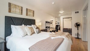 A modern bedroom with a large bed, a desk, and a mirror. - Charming Downtown Cottage (Colorado Springs)