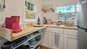 A kitchen with white cabinets, a wooden countertop, a red coffee maker, and a stainless steel refrigerator. - Charming Downtown Cottage (Colorado Springs)
