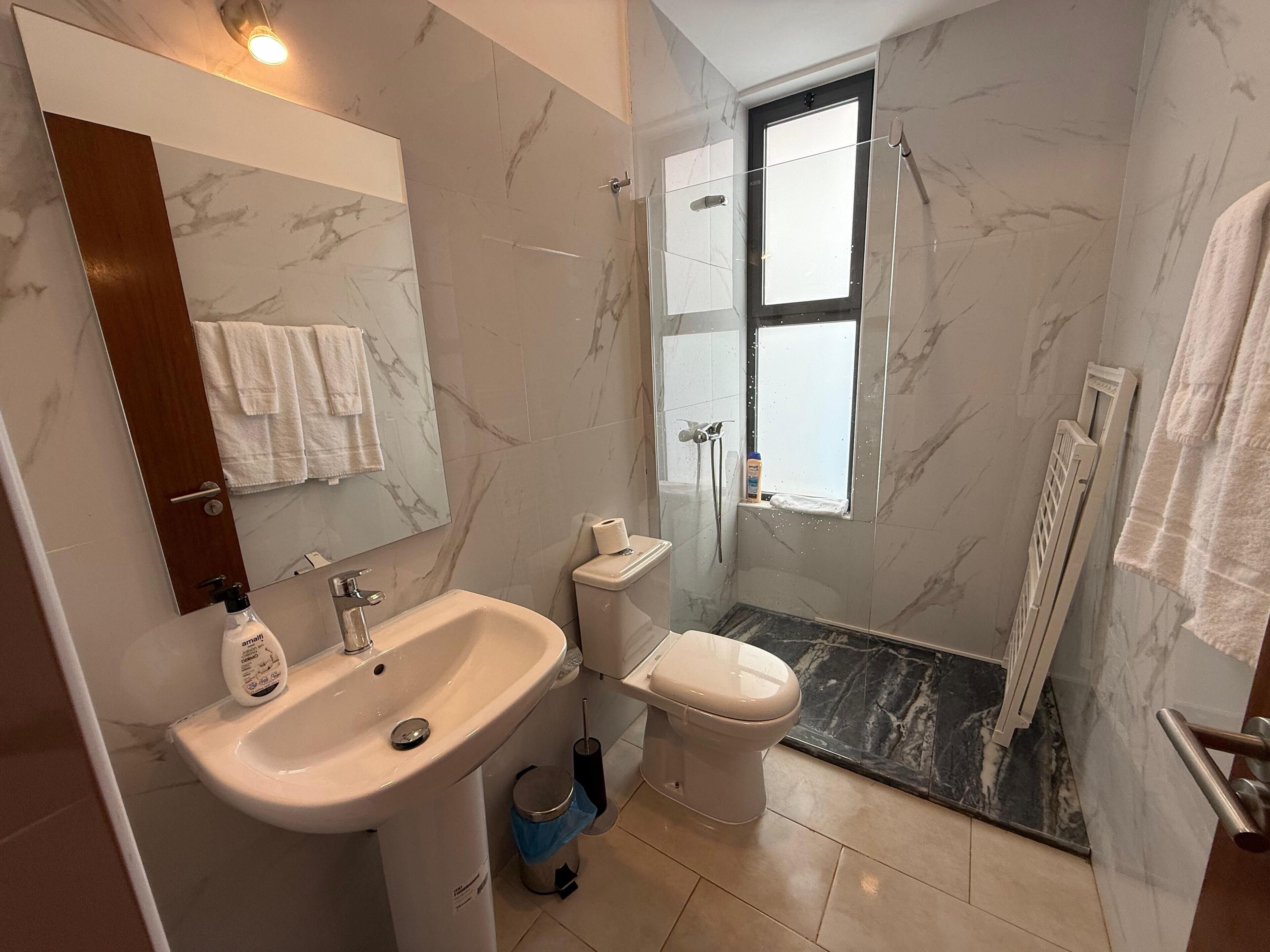 A bathroom with a marble sink, toilet, and shower.