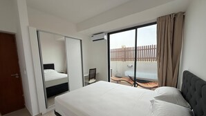 A hotel room with a bed, a chair, a small table, and a balcony with a view. - Joli Beach House - Spacious Ground Floor T2 Apartment (Sal)