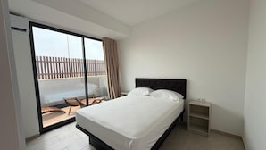 A bedroom with a bed, a nightstand, and a view of a balcony with a wooden fence. - Joli Beach House - Spacious Ground Floor T2 Apartment (Sal)