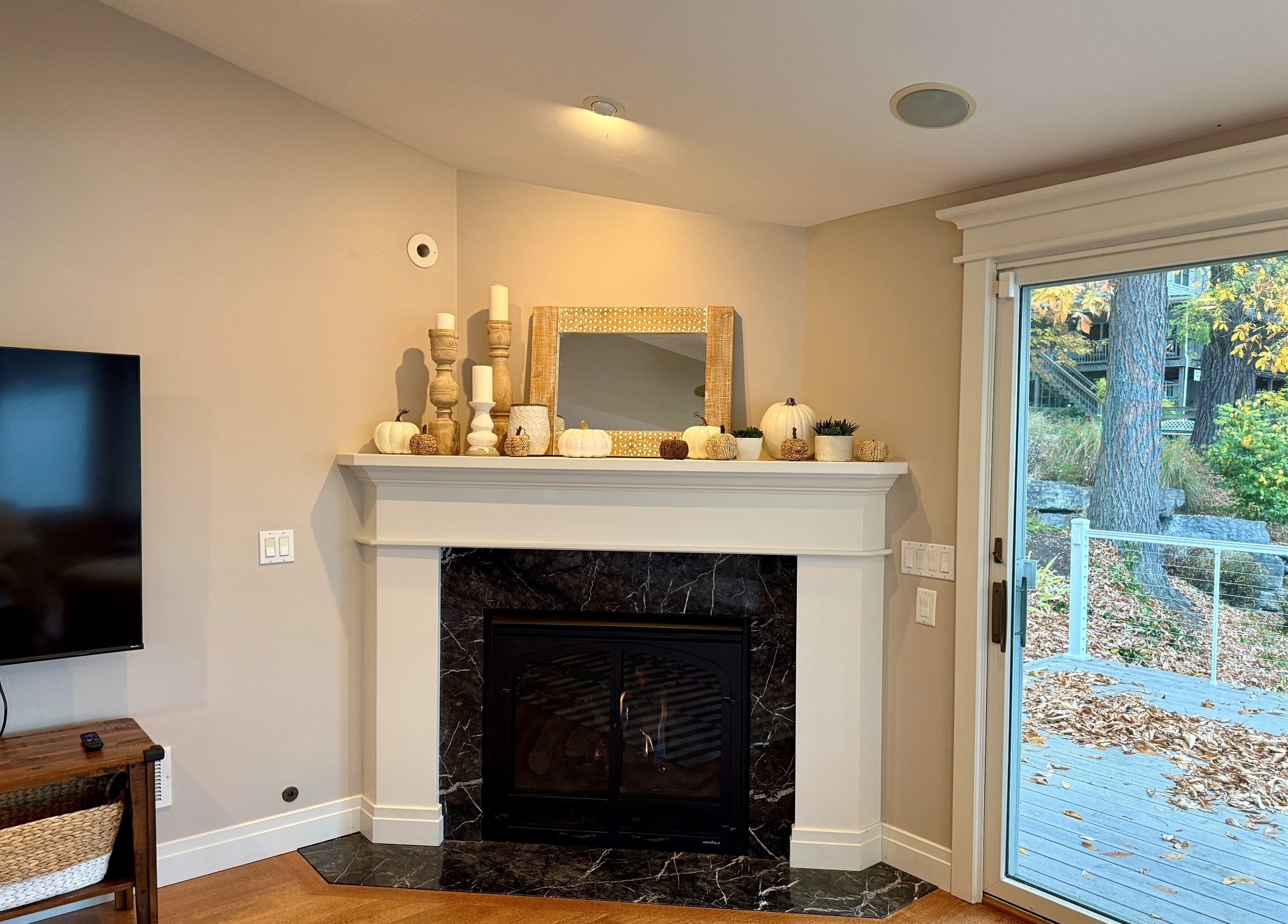 A living room with a fireplace, a television, and a door leading to an outdoor area.