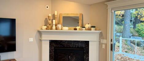 A living room with a fireplace, a television, and a door leading to an outdoor area.