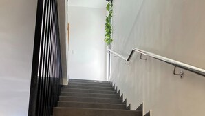 Un escalier avec une rampe métallique et une plante fixée au mur.