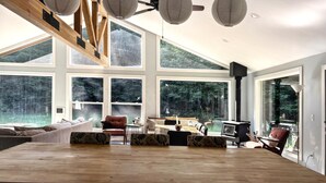 Un salon spacieux doté de grandes fenêtres, d’un plafond en bois et d’une cheminée.