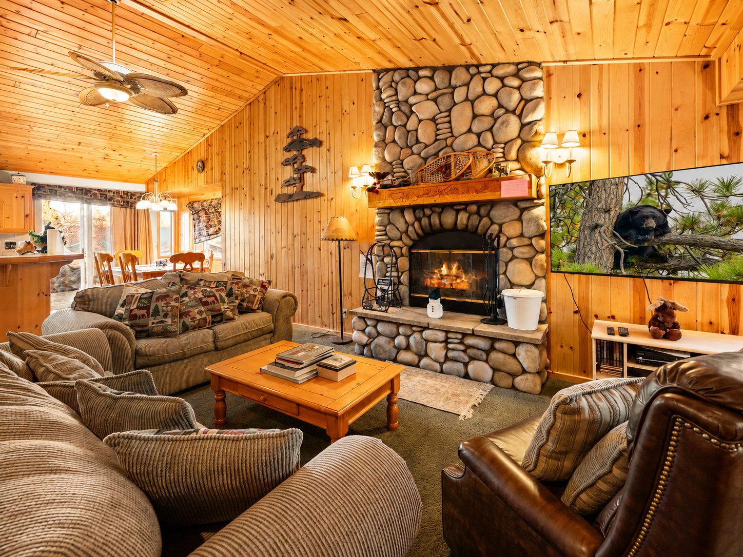 Interior acogedor de una cabaña con chimenea de piedra, paredes de madera y una zona de estar confortable.