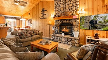 Interior acogedor de una cabaña con chimenea de piedra, paredes de madera y una zona de estar confortable.