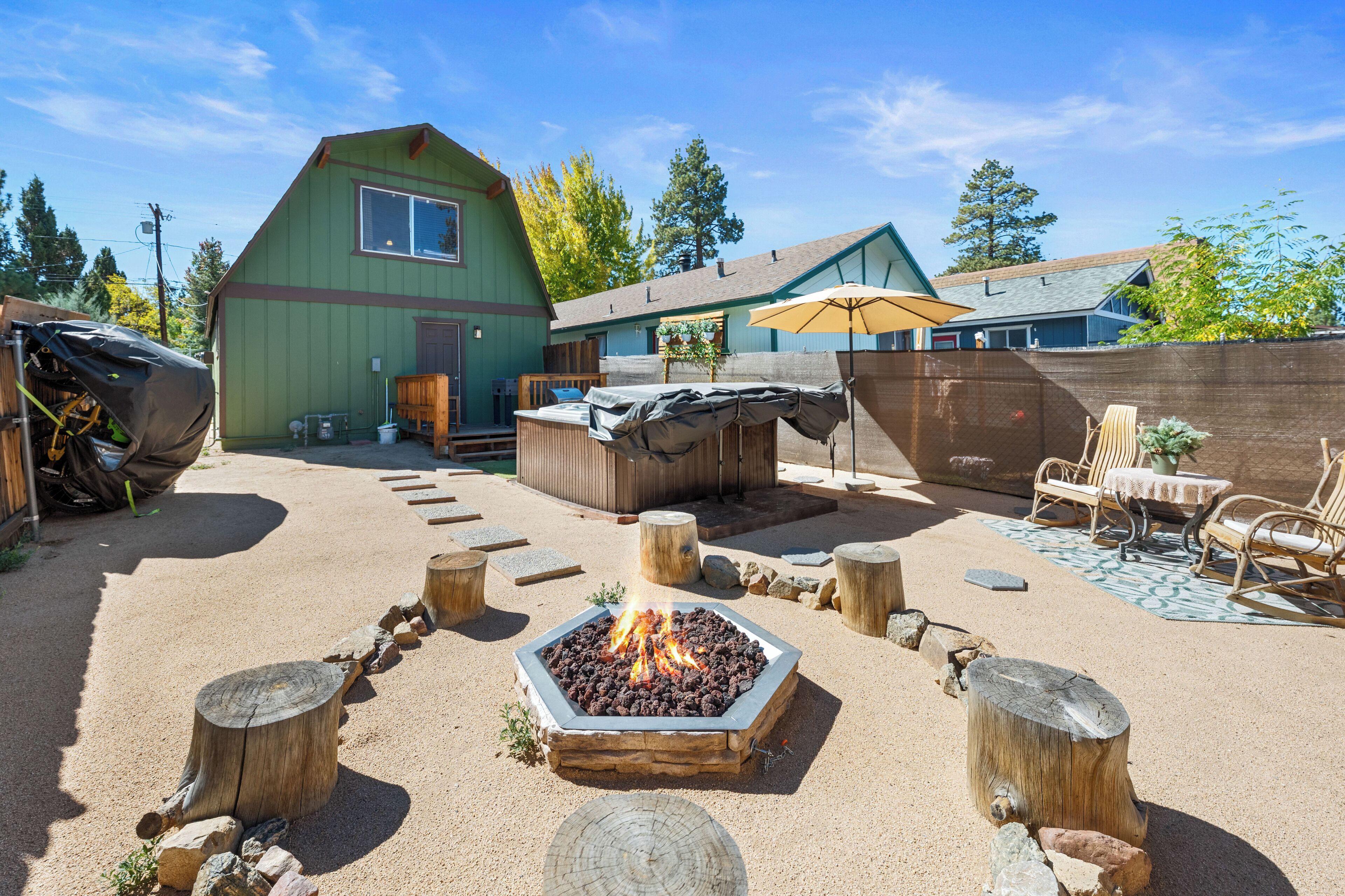 Un patio trasero con una chimenea, mobiliario exterior y una zona de barbacoa techada.