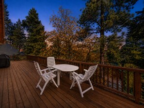 A wooden deck with a round table and four chairs, surrounded by a railing.
