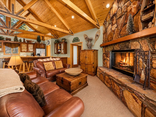 Una sala de estar acogedora con chimenea, sofá de cuero y una pared de acento de piedra.