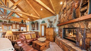 A spacious living room with a fireplace, leather furniture, and a stone accent wall. - The Getaway Chalet - Walk to Slopes & Golf Course, Ping Pong, Fireplace, Deck (Big Bear Lake)