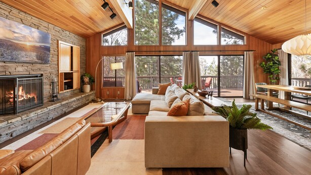 A spacious living area with a fireplace, large windows, and a wooden ceiling. - Modern Primrose - Spacious 3 BR Mountain Cabin | Decks, A/C, Game Room & Near Ski, Zoo & Golf (Big Bear Lake)