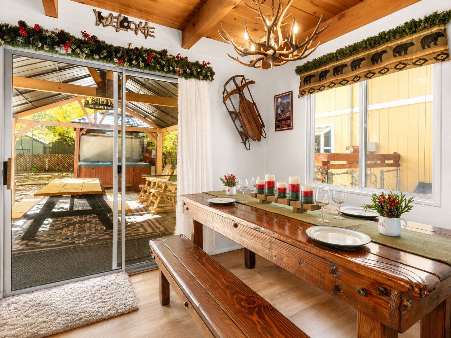 A wooden dining table with benches, a chandelier, and a view of the backyard.