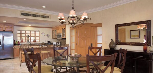A spacious kitchen with a dining area, featuring a chandelier, wooden cabinets, and a large mirror.
