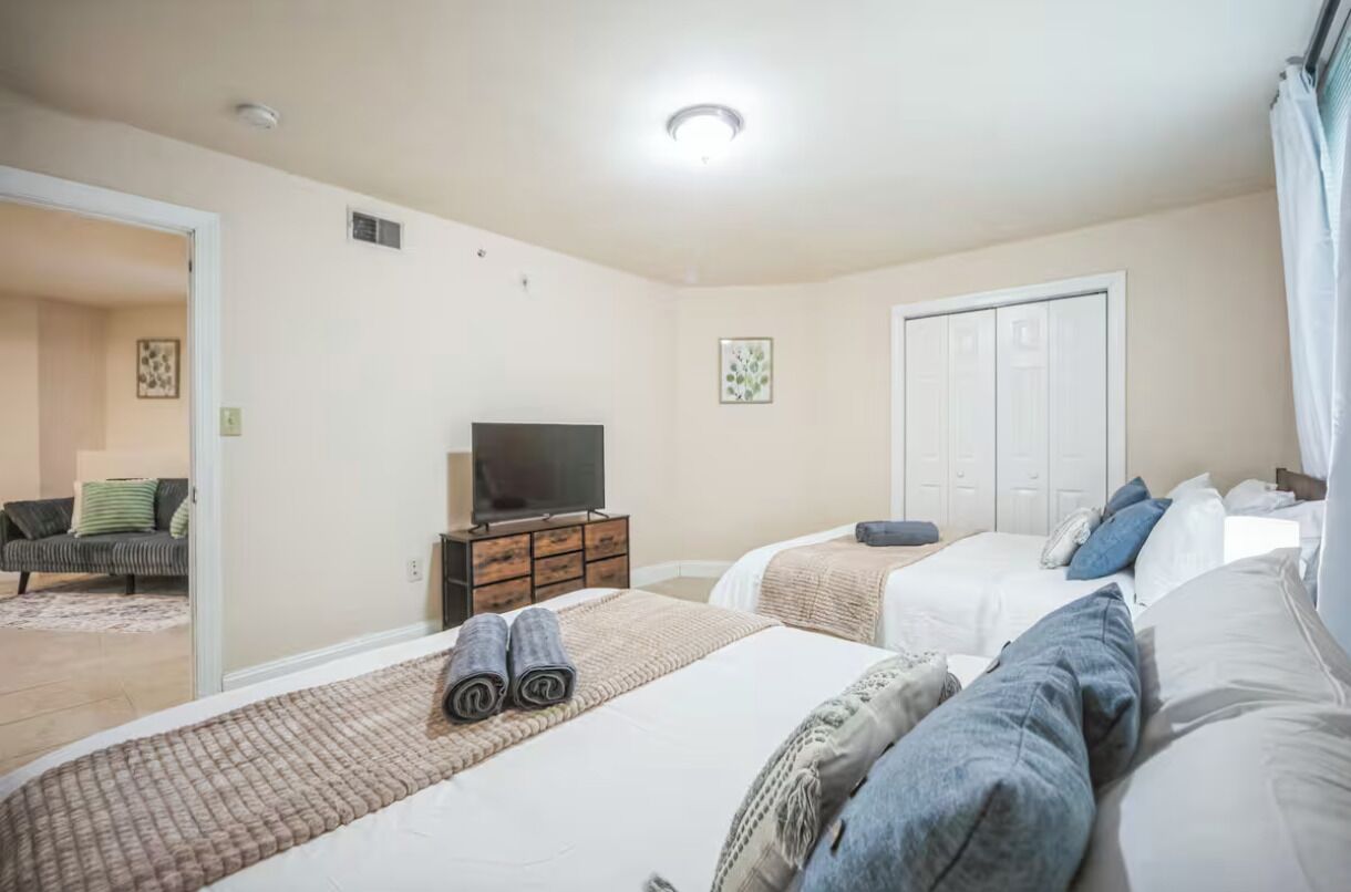 A hotel room with two beds, a TV, and a wardrobe.