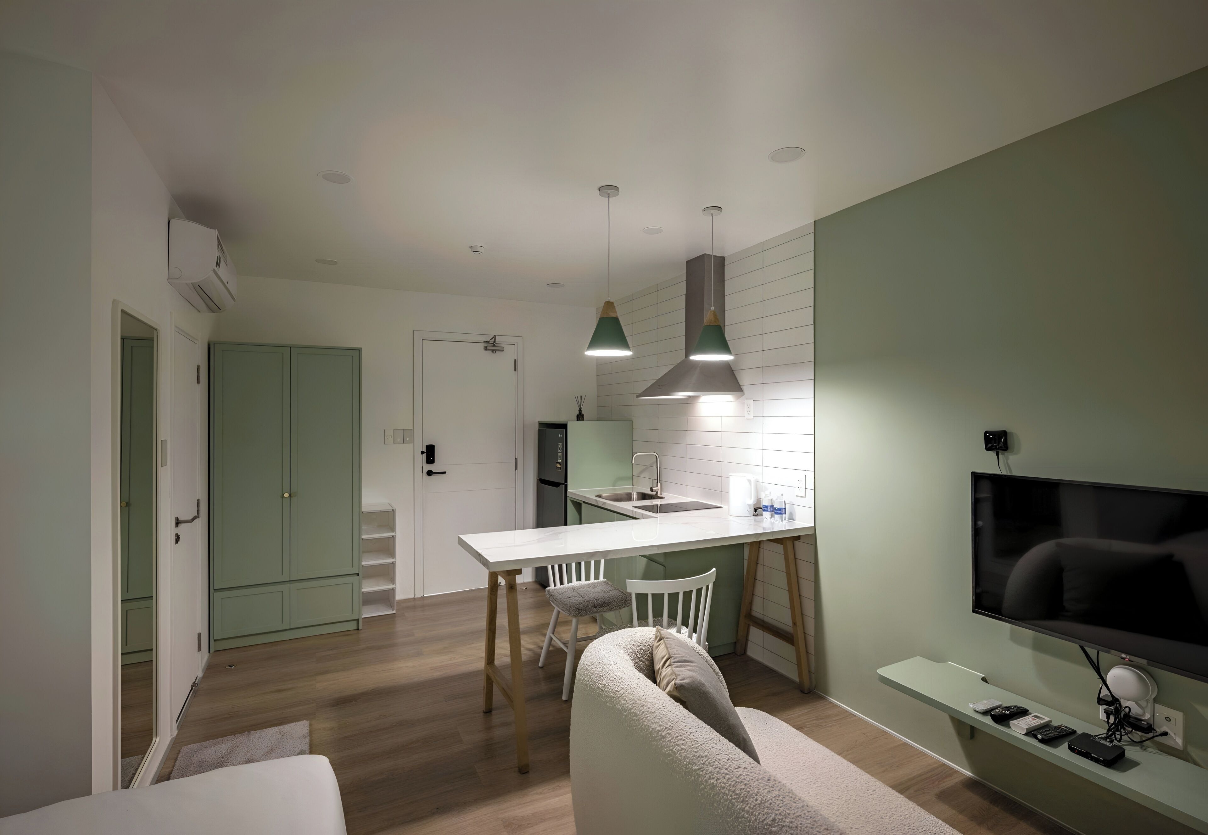 A modern kitchen with a dining area, a TV, and a sofa.