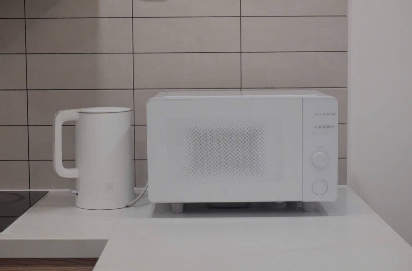A white microwave and a white coffee maker on a white countertop.